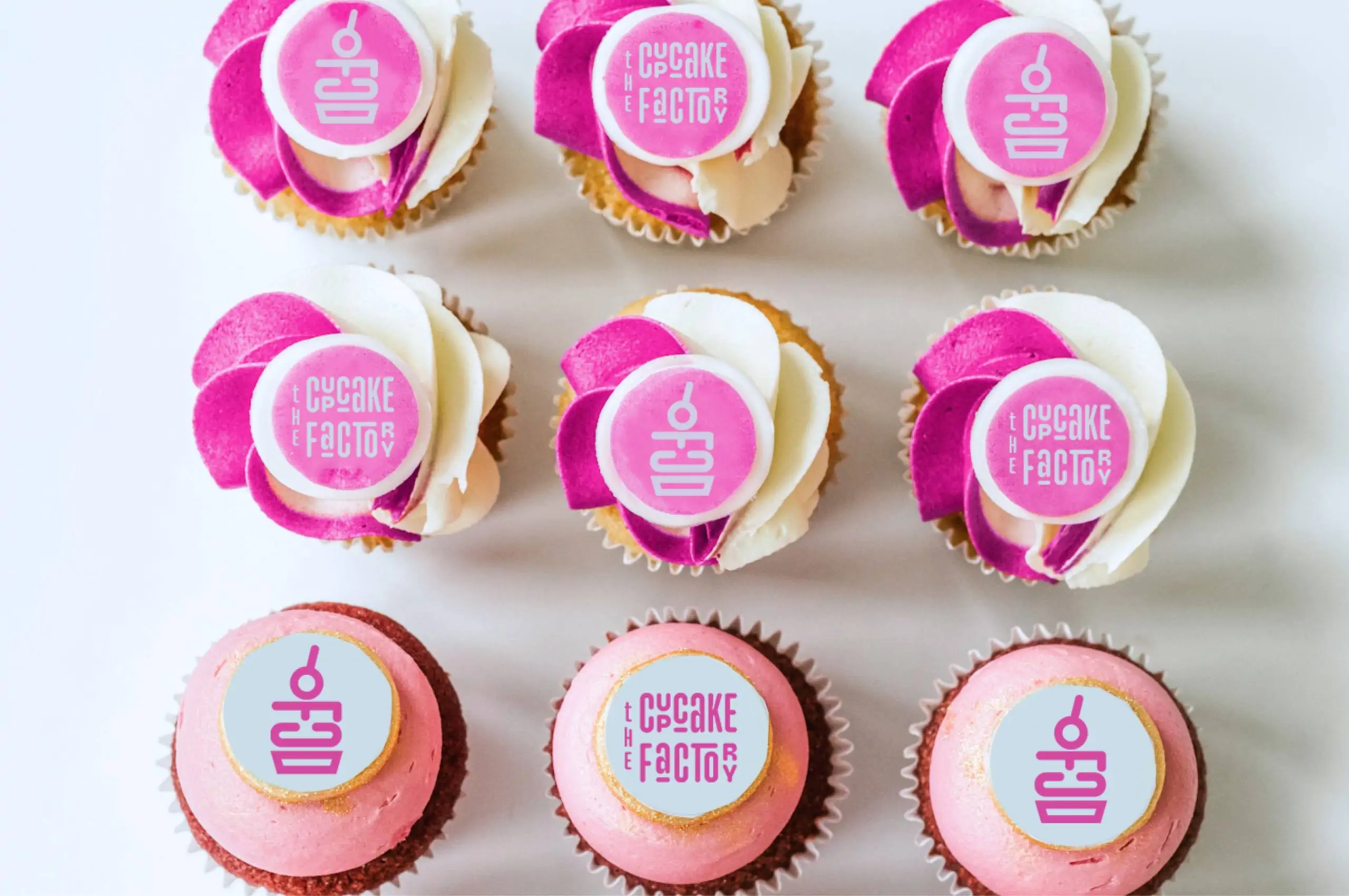 a group of logo cupcakes with pink frosting